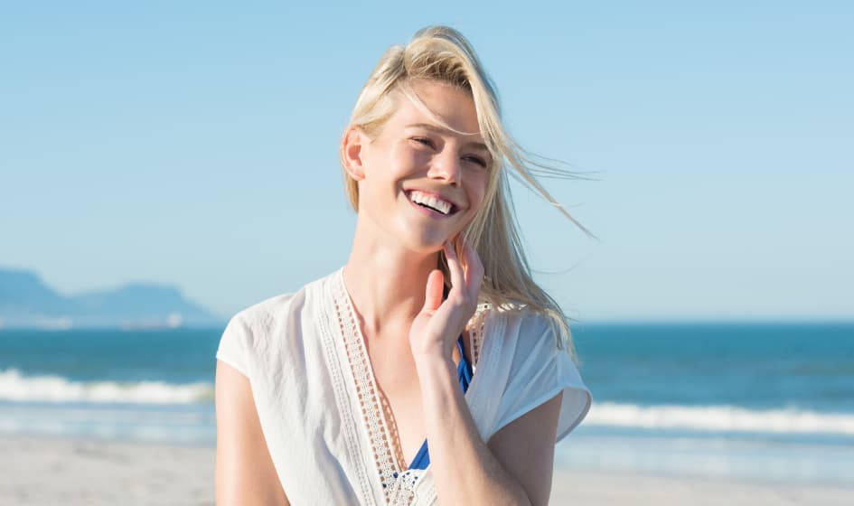 A beautiful woman is smiling after Invisalign treatments.