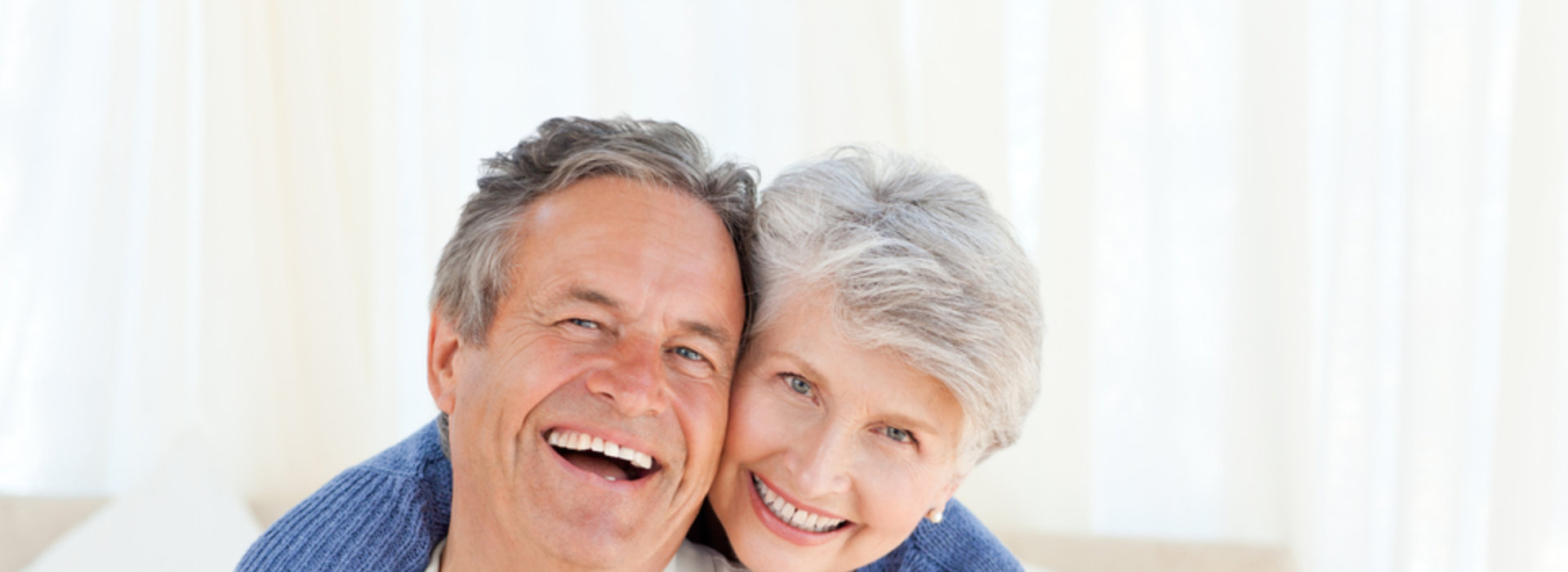 A senior couple is smiling while wearing dentures.