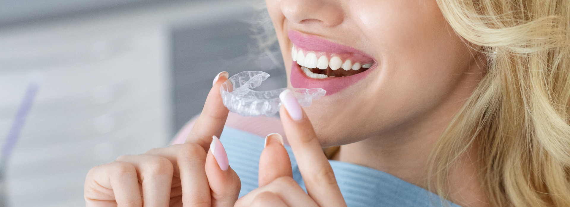 A woman holding a set of Invisalign braces.