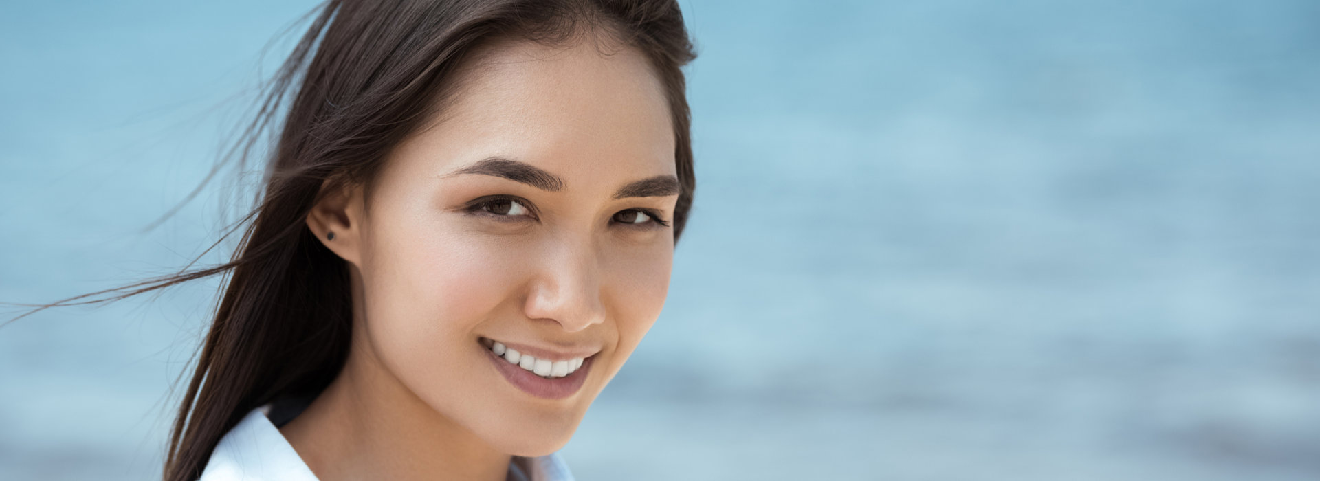 A woman is smiling after receiving porcelain crowns treatment.