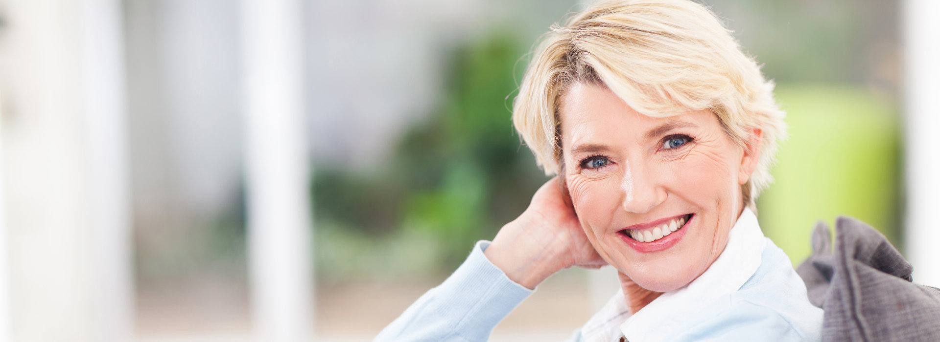 A woman is smiling after receiving dental implants.